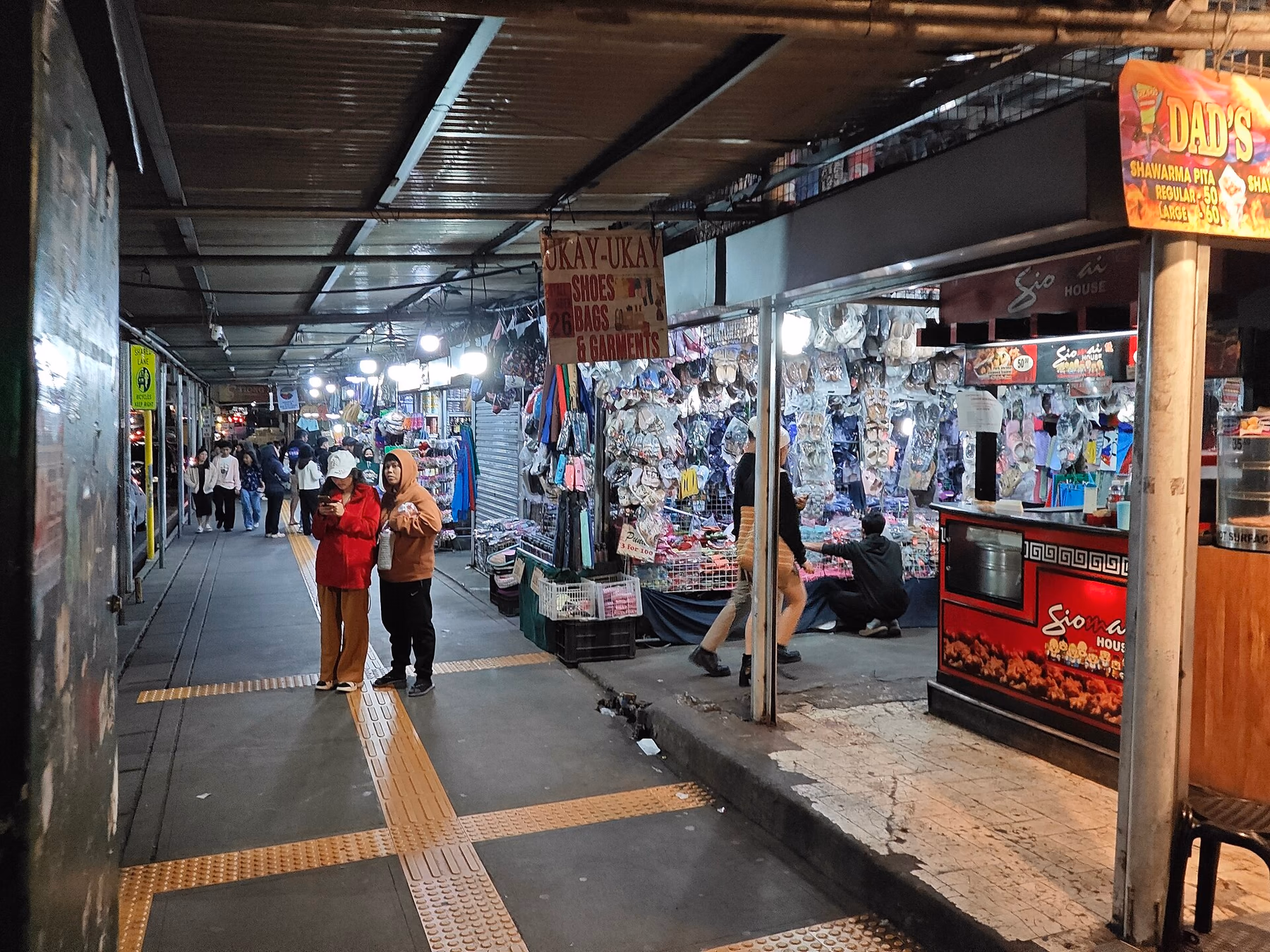 Ukay-ukay, shoe and food stalls beside a pedestrian path at night